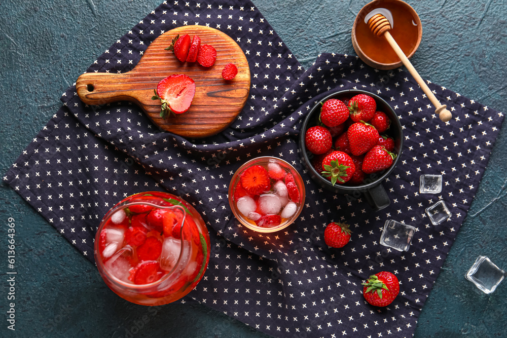 Glass and jug of infused water with strawberry on black background