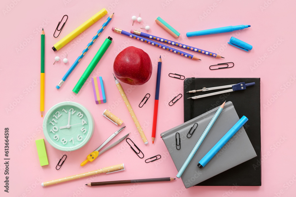 Fresh red apple with alarm clock and different stationery on pink background