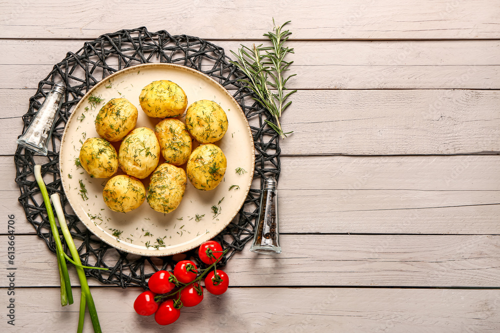 Plate of boiled baby potatoes with dill and tomatoes on grey wooden background