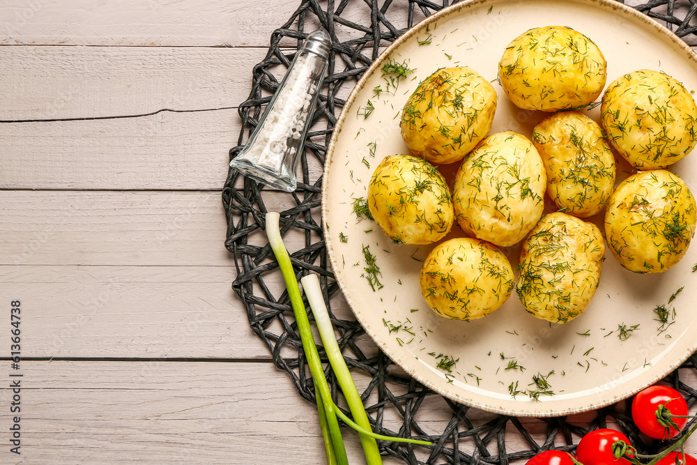 Plate of boiled baby potatoes with dill and tomatoes on grey wooden background