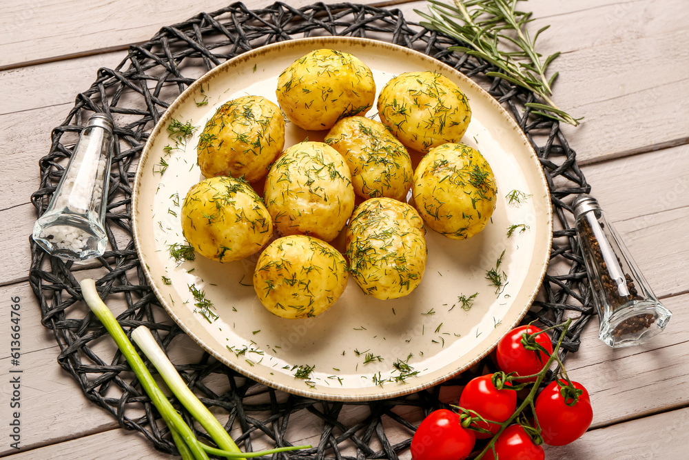 Plate of boiled baby potatoes with dill and tomatoes on grey wooden background