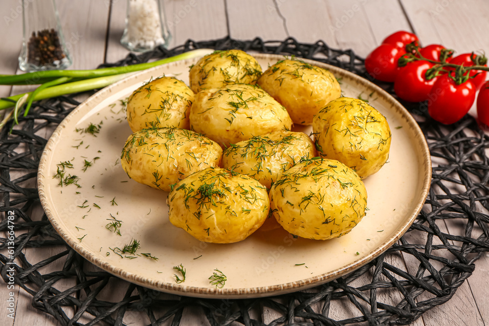 Plate of boiled baby potatoes with dill and tomatoes on grey wooden background