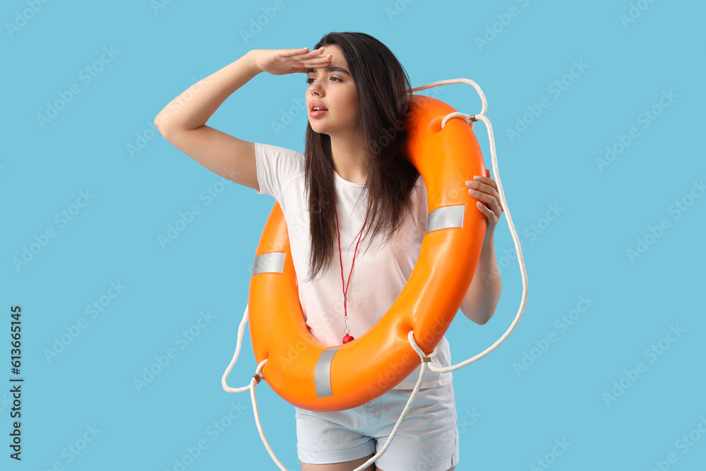 Female lifeguard with ring buoy on blue background