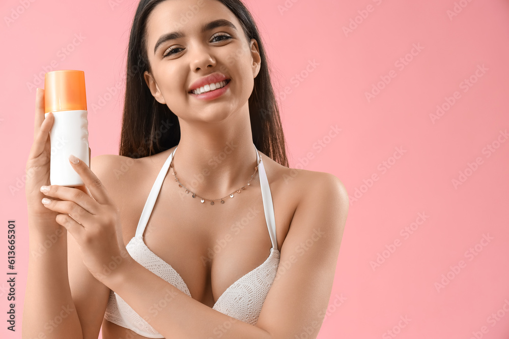 Young woman with sunscreen cream on pink background, closeup