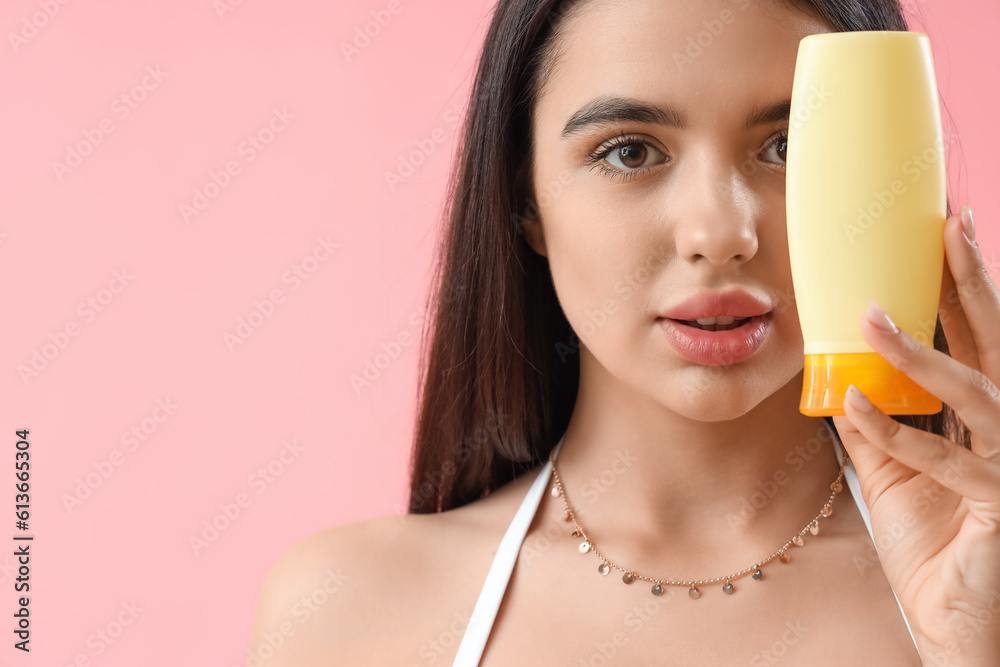 Young woman with sunscreen cream on pink background, closeup