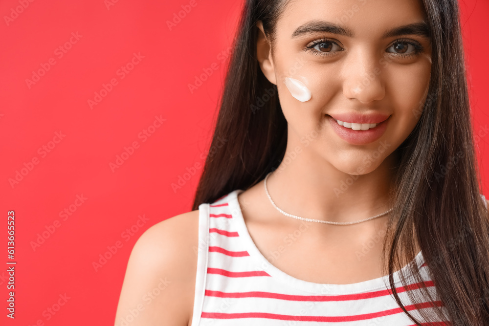 Young woman with sunscreen cream on her face against red background, closeup