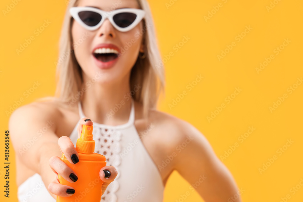 Young woman with sunscreen cream on yellow background, closeup