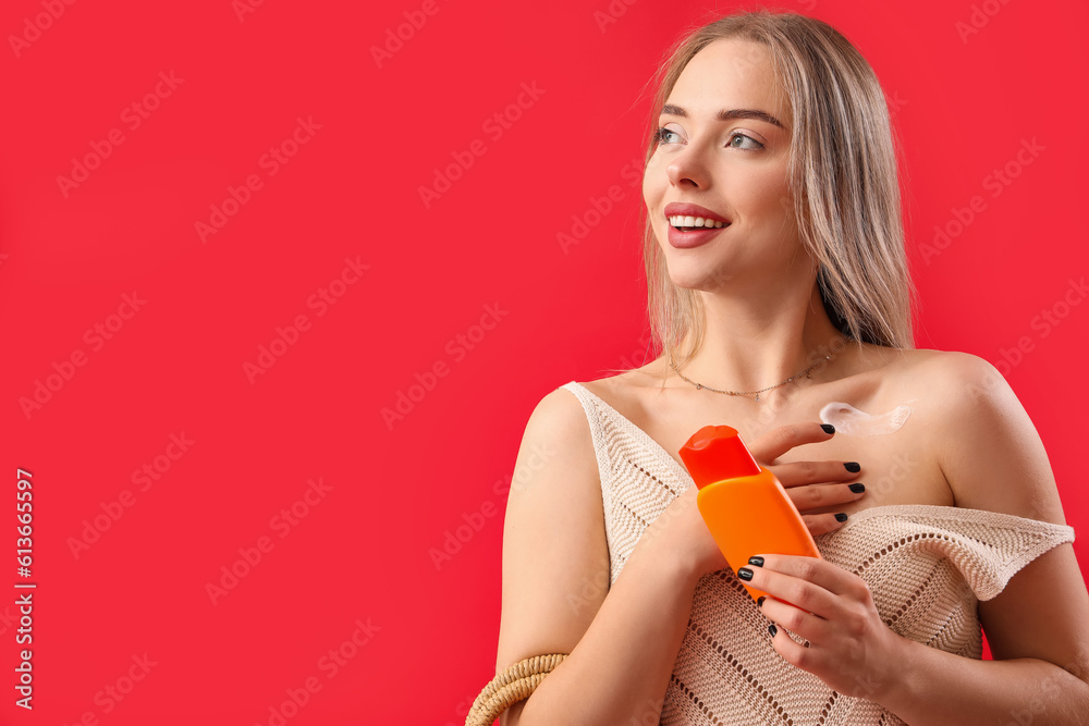 Young woman with sunscreen cream on red background