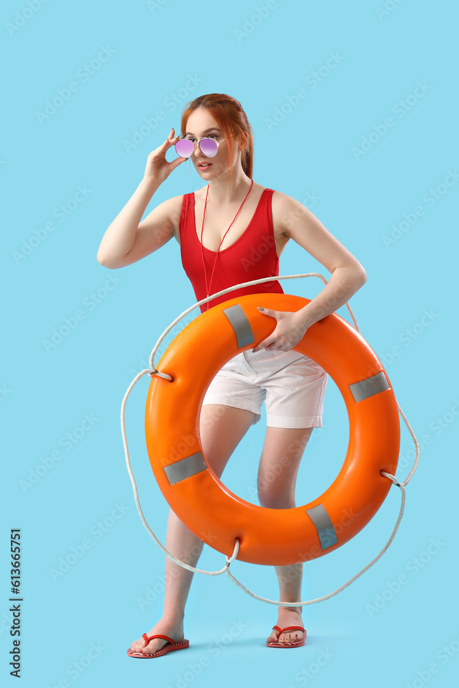 Female lifeguard with ring buoy on blue background