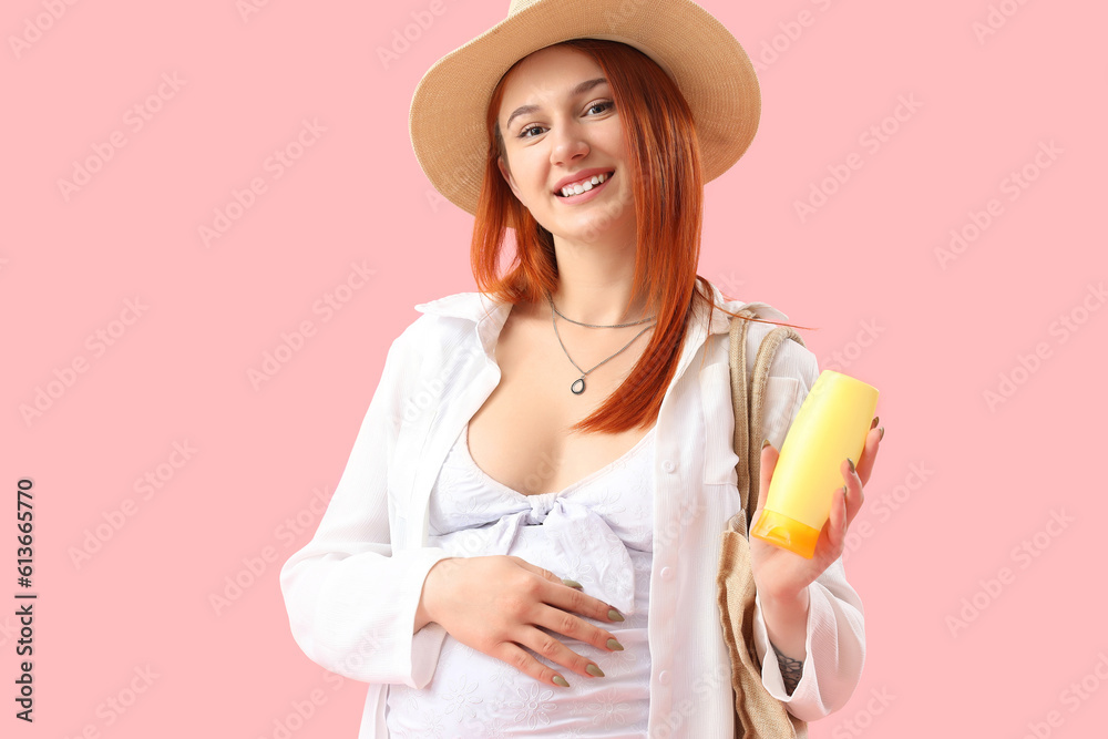 Young pregnant woman with sunscreen cream on pink background