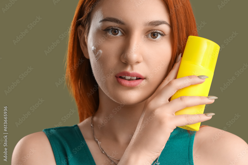 Young woman with heart made of sunscreen cream on green background