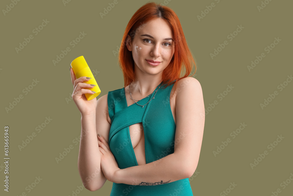 Young woman with heart made of sunscreen cream on green background