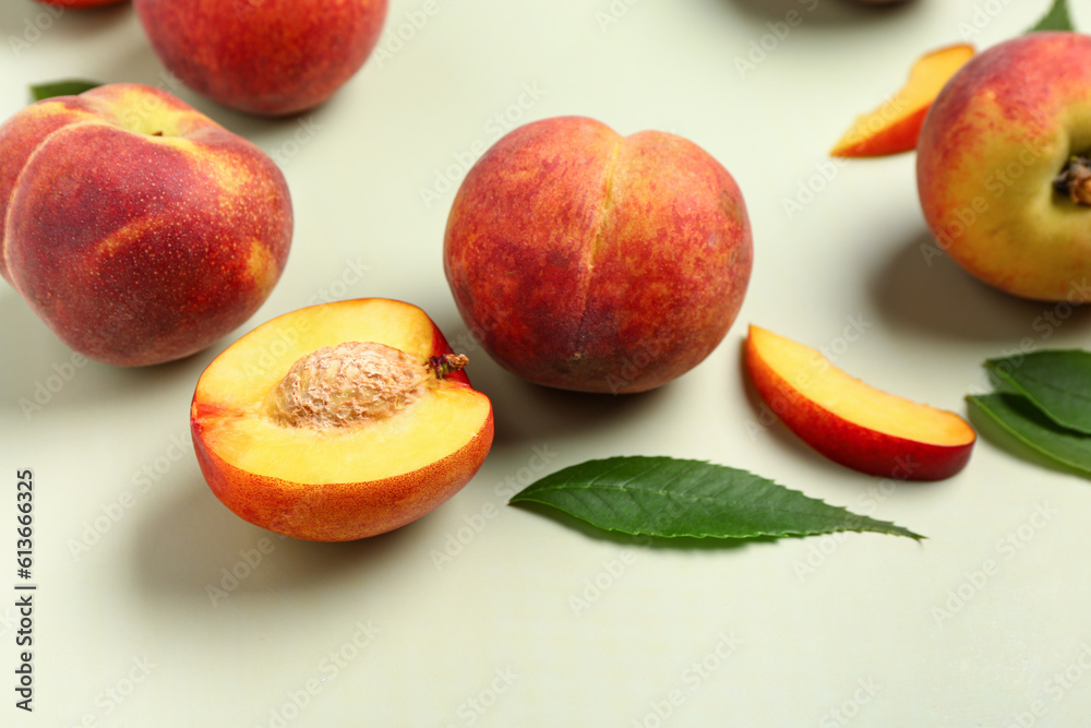 Sweet peaches and leaves on light background