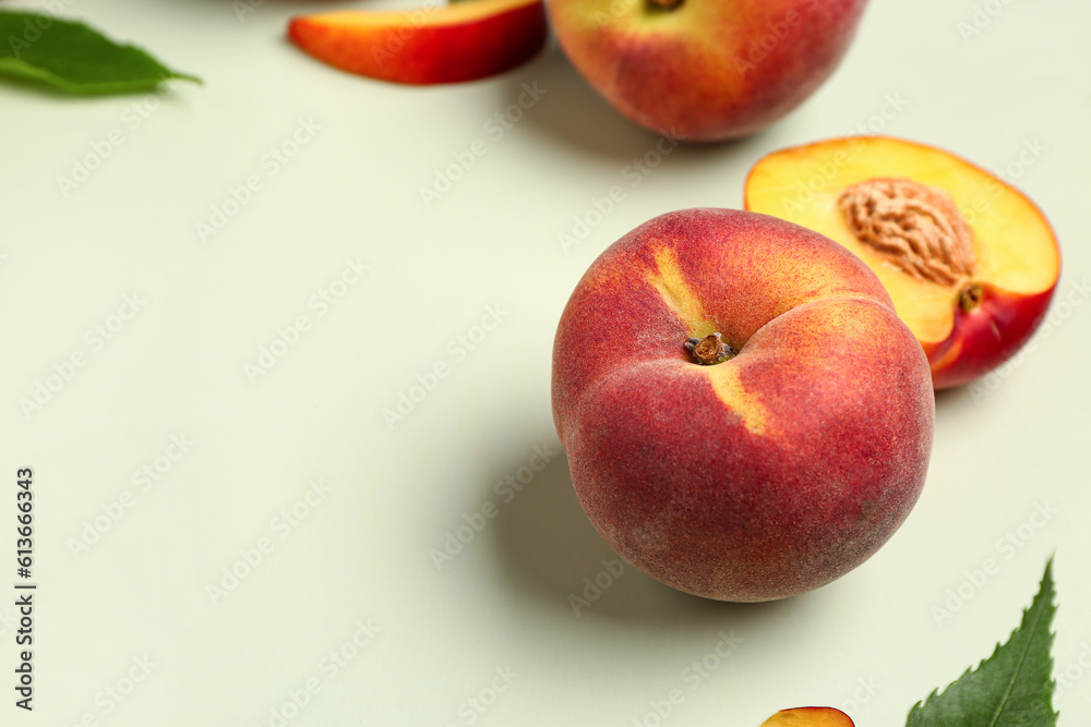 Sweet peaches and leaves on light background