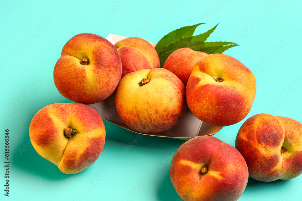 Paper plate with sweet peaches and leaves on blue background