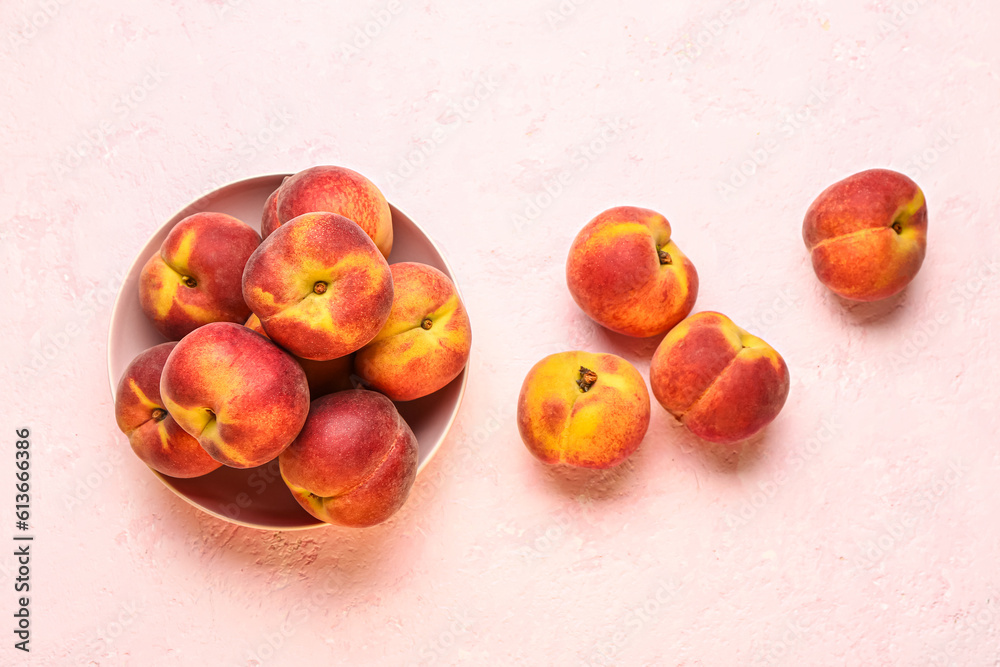 Bowl with sweet peaches on pink background