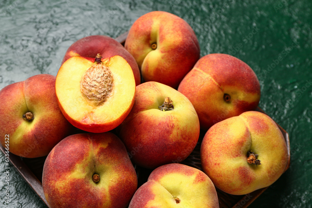 Tray with sweet peaches on green background