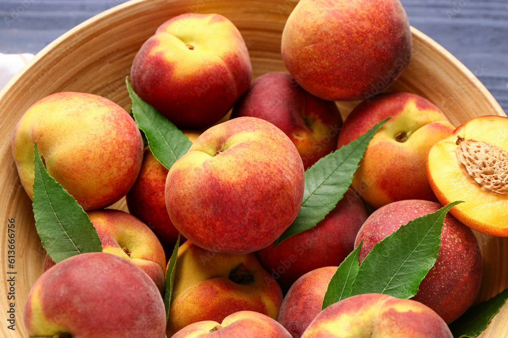 Bowl with sweet peaches and leaves, closeup