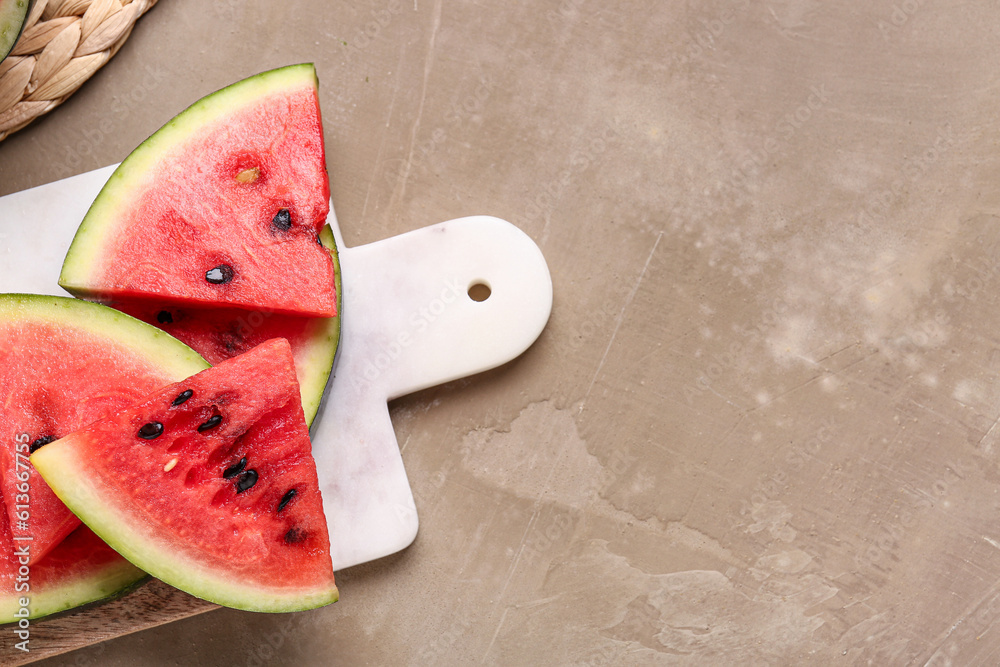 Board with pieces of fresh watermelon on brown background