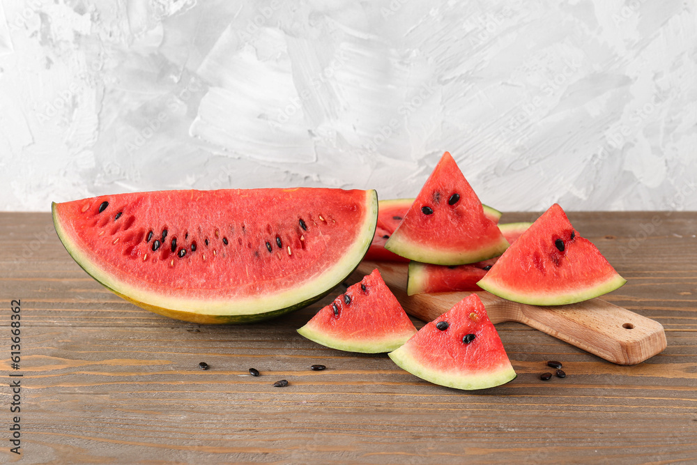 Board with pieces of fresh watermelon and seeds on wooden table