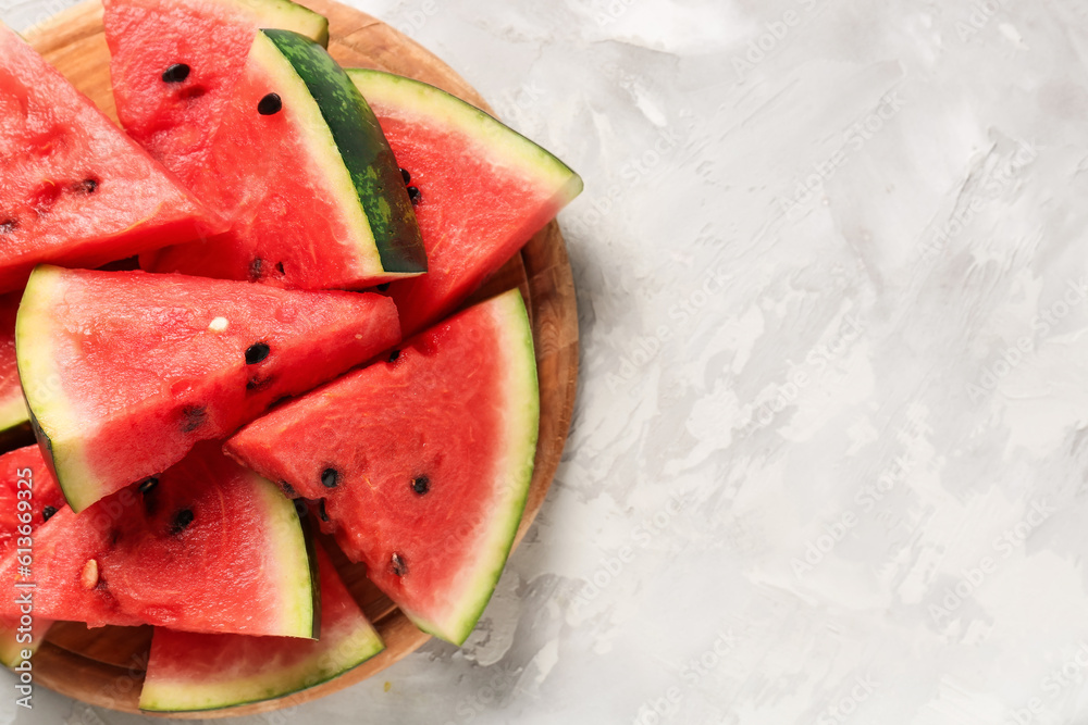 Board with pieces of fresh watermelon on grey background