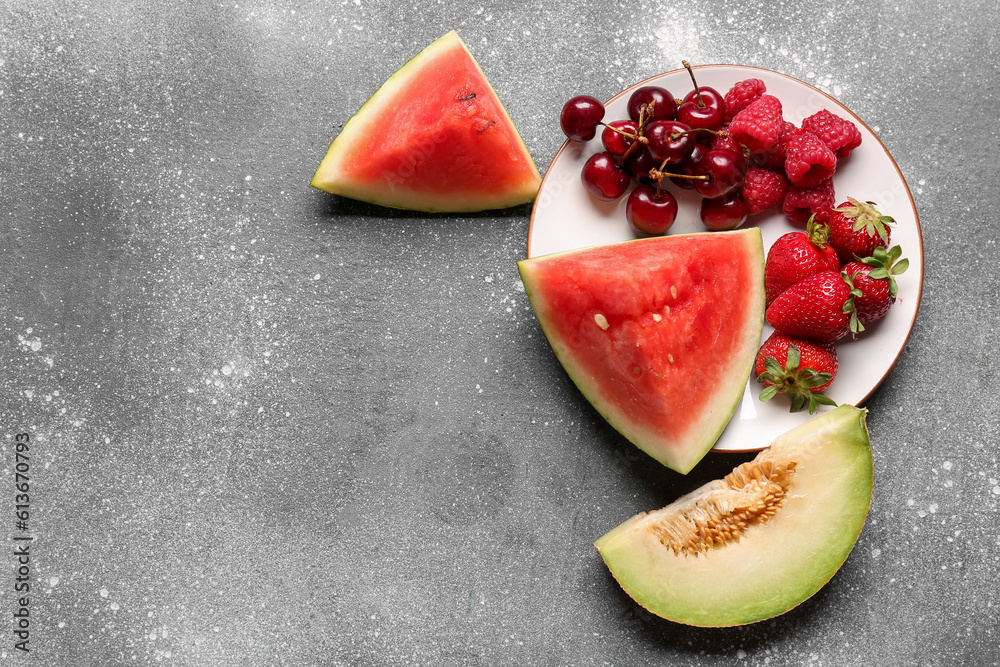 Plate with pieces of fresh watermelon and different berries on grey background