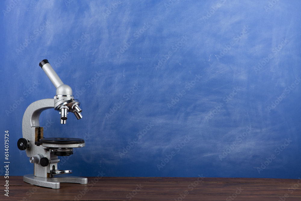 Back to school - microscope on the desk, Education concept. Blackboard background