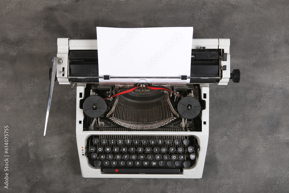 vintage typewriter on the table with blank paper on the grey desk - concept for writing, journalism,