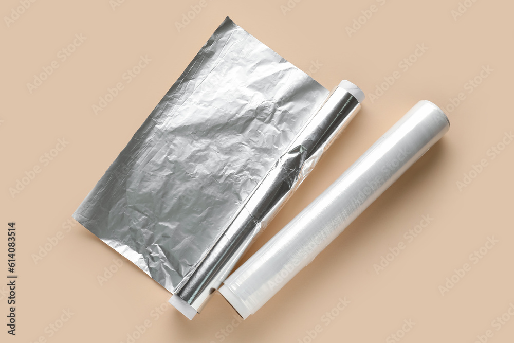 Rolls of aluminium foil and food film on color background