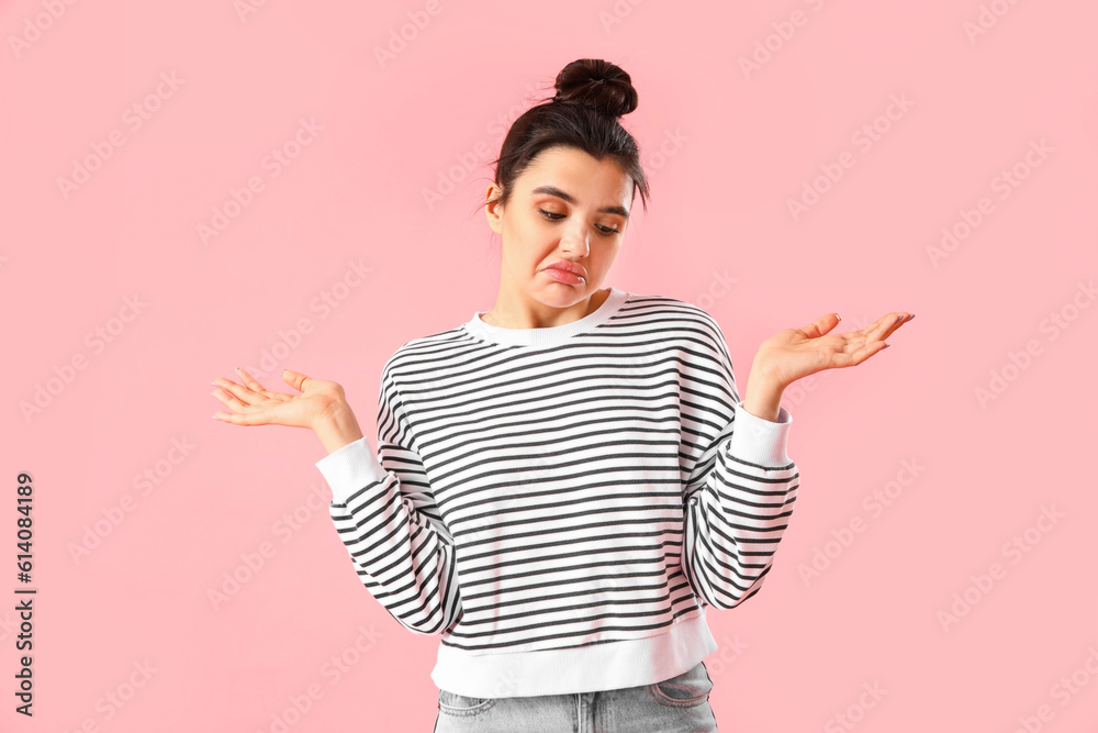 Confused young woman on pink background