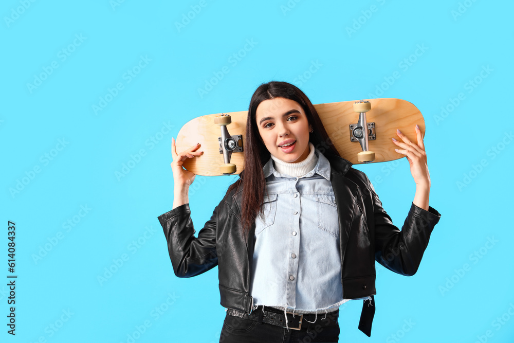 Stylish young woman with skateboard on blue background