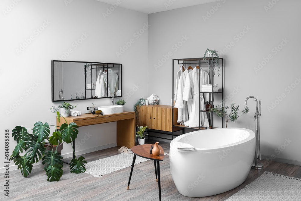 Interior of light bathroom with shelving unit, mirror and sink