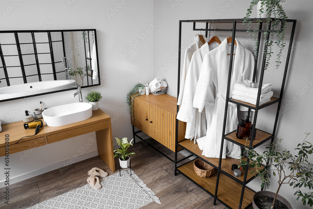 Interior of light bathroom with shelving unit, mirror and sink