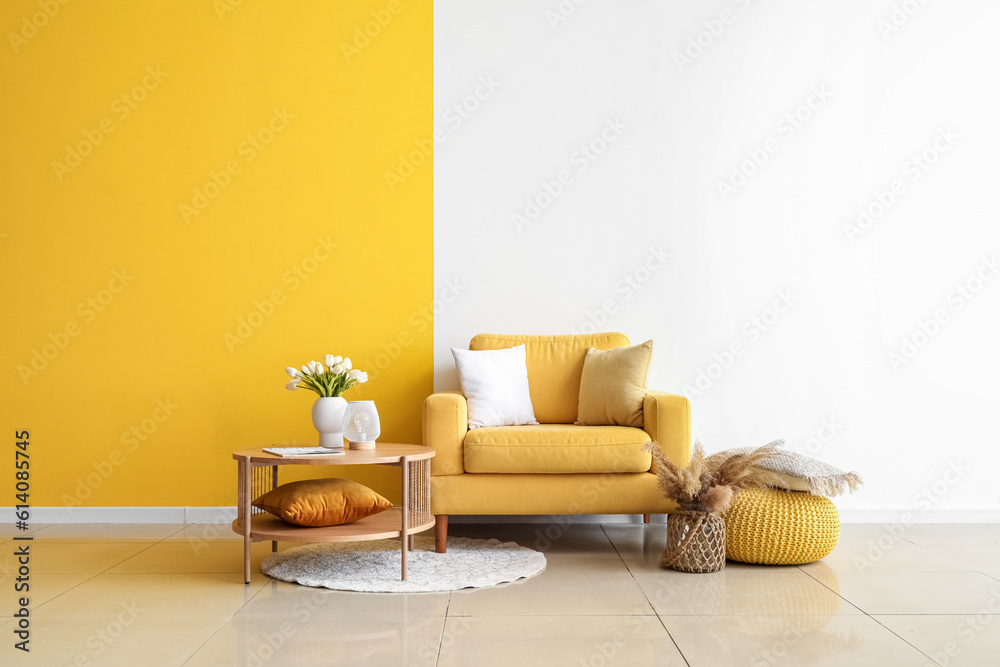 Cozy armchair and coffee table with tulip flowers in vase near colorful wall