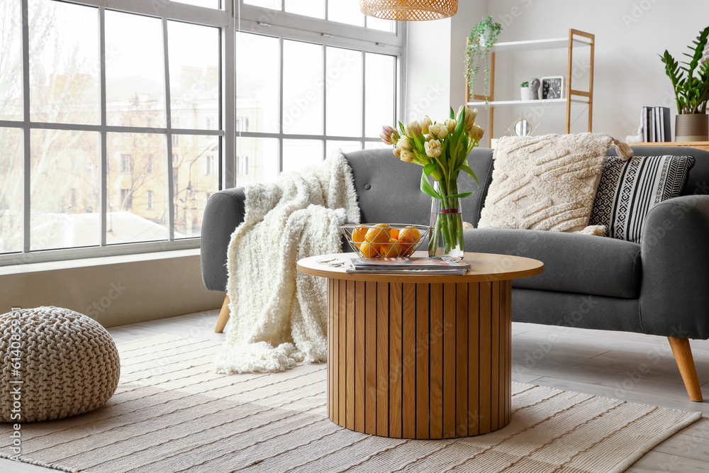 Interior of stylish living room with cozy sofa and coffee table near big window