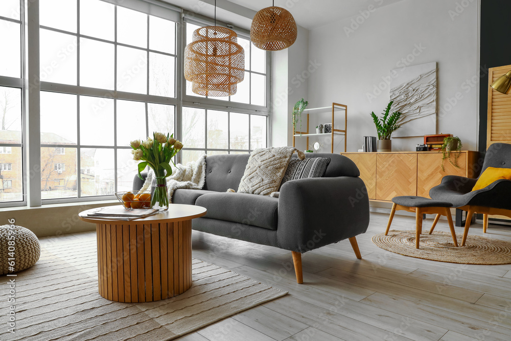 Interior of stylish living room with cozy sofa and coffee table near big window