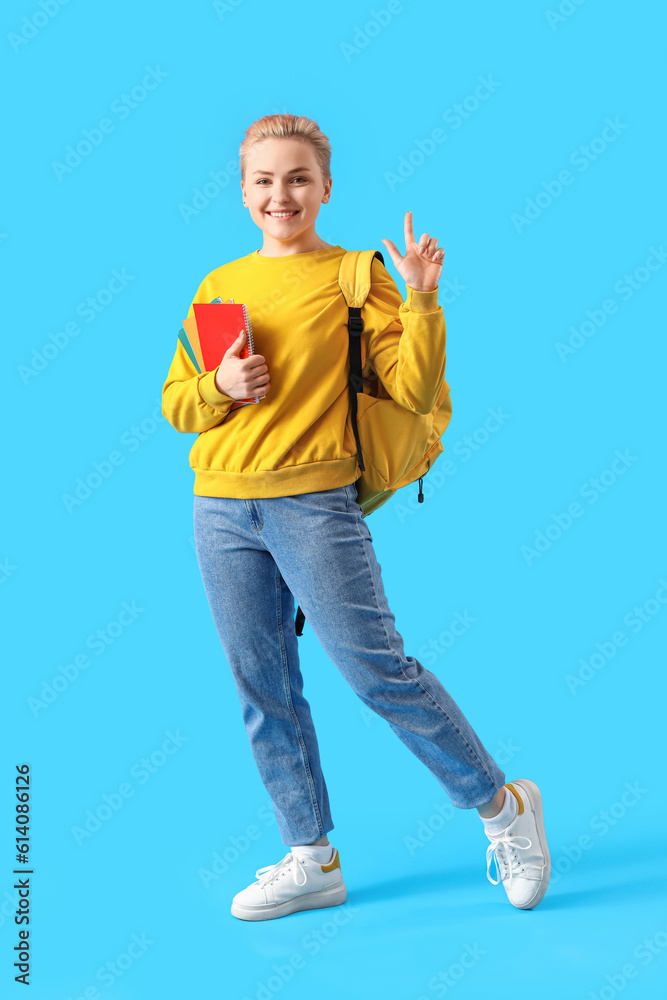 Female student with notebooks on blue background