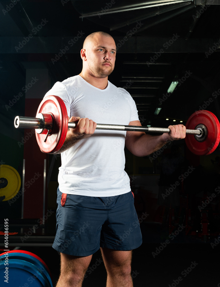 Male athlete lifts the barbell