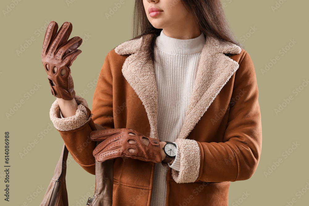 Stylish young woman in leather gloves with bag on green background, closeup