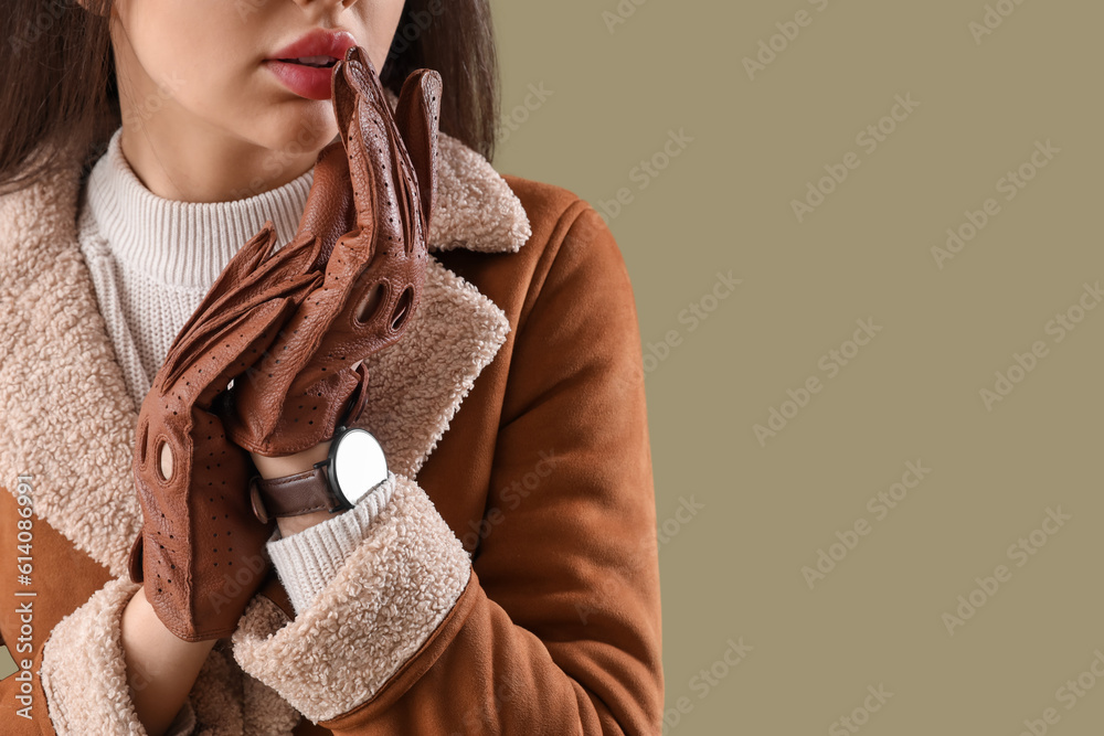 Stylish young woman in leather gloves on green background, closeup