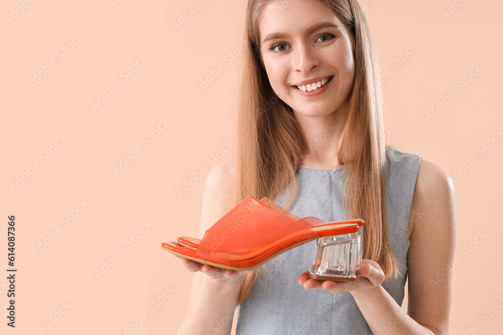 Young woman with shoes on beige background, closeup