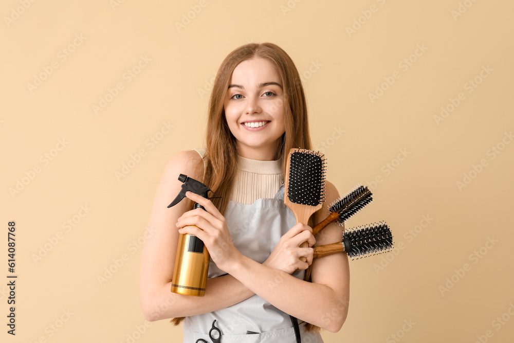 Female hairdresser with brushes and spray on beige background