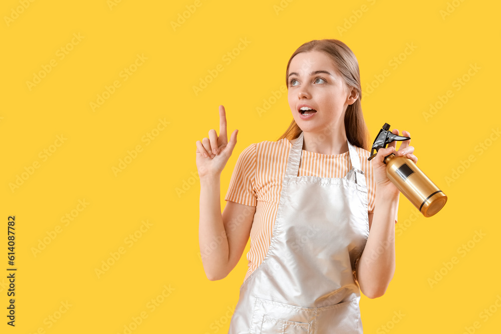 Female hairdresser with spray on yellow background