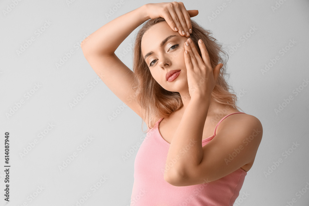 Young woman doing face building exercise on light background