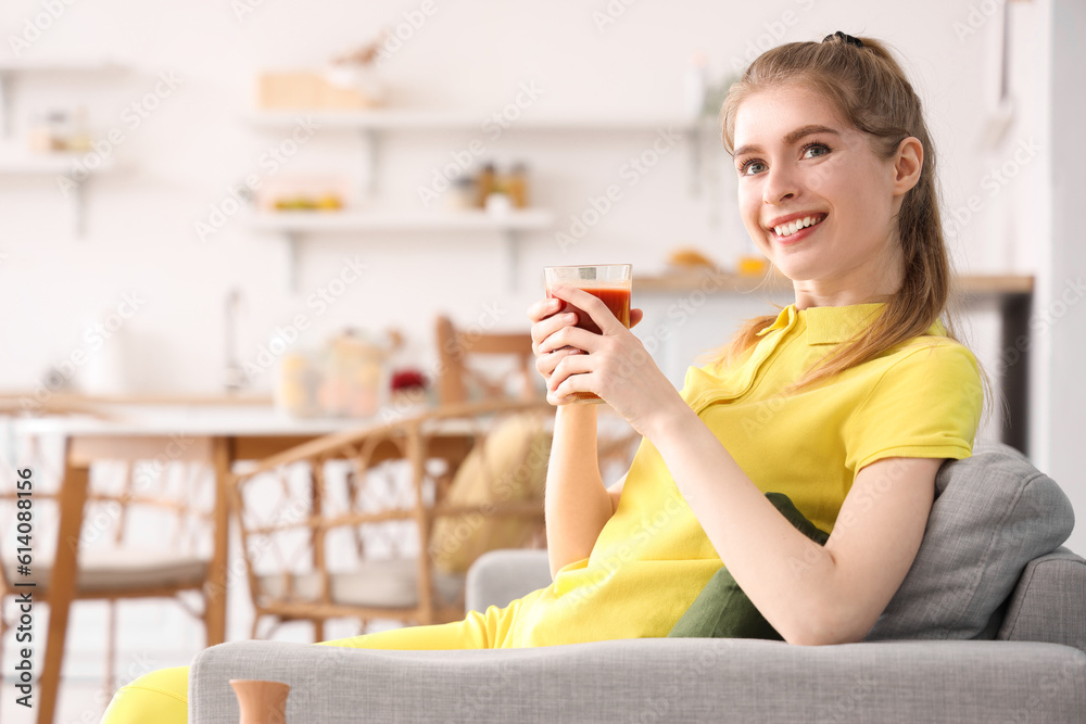 Sporty young woman with glass of vegetable juice in kitchen