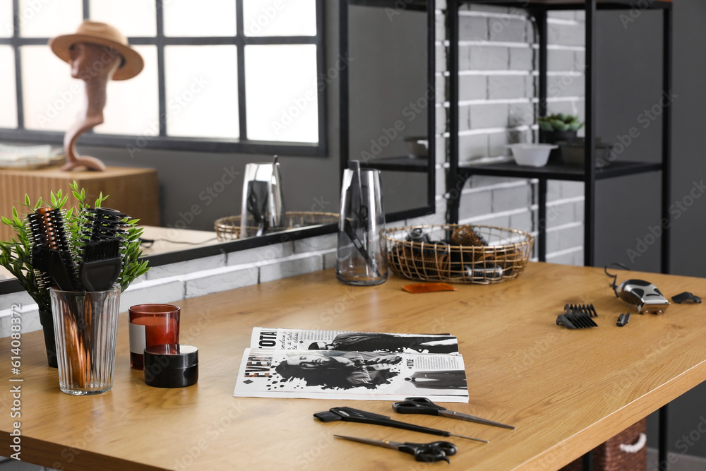 Different hairdressing tools and magazine on table in beauty salon