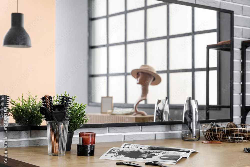 Different hairdressing tools and magazine on table in beauty salon