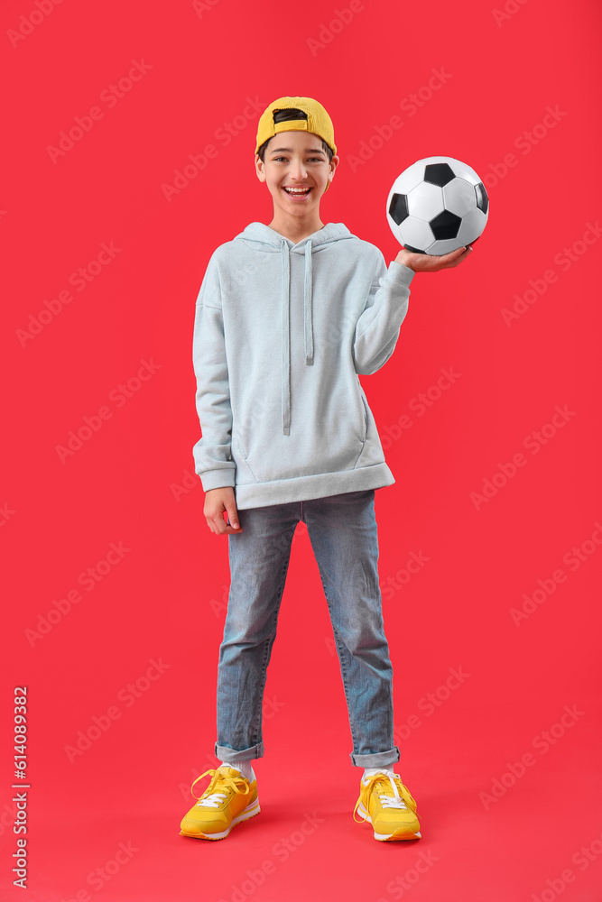 Little boy with soccer ball on red background