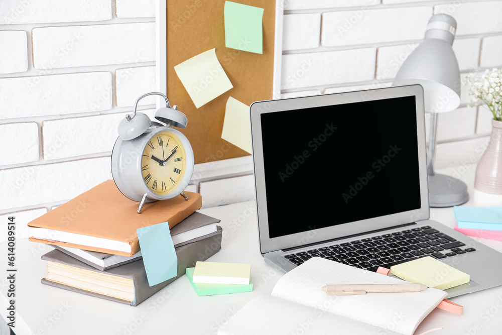 Laptop with sticky notes on white table