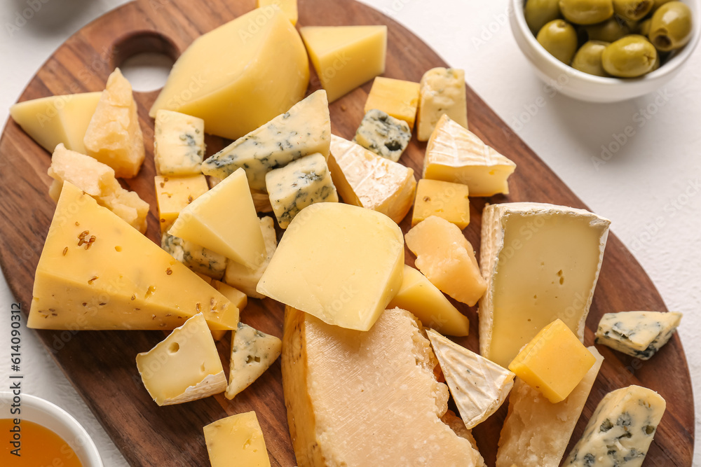 Wooden board with pieces of tasty cheese on table, closeup